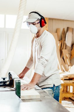 Carpenter working cutting some boards, he is wearing safety glasses and hearing protection