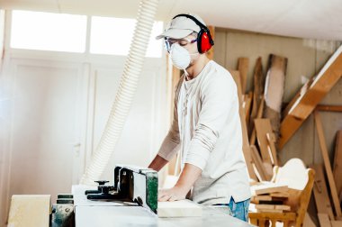 Carpenter working cutting some boards, he is wearing safety glasses and hearing protection