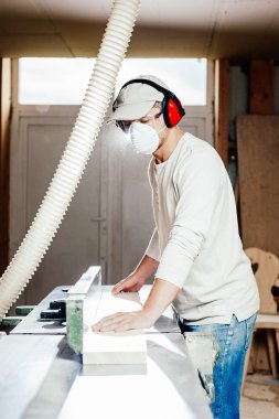 Carpenter working on wood machine in factory