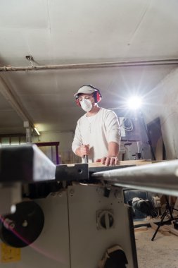 Carpenter working on wood machine in factory