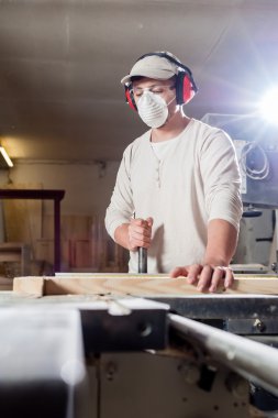 Carpenter working on wood machine in factory