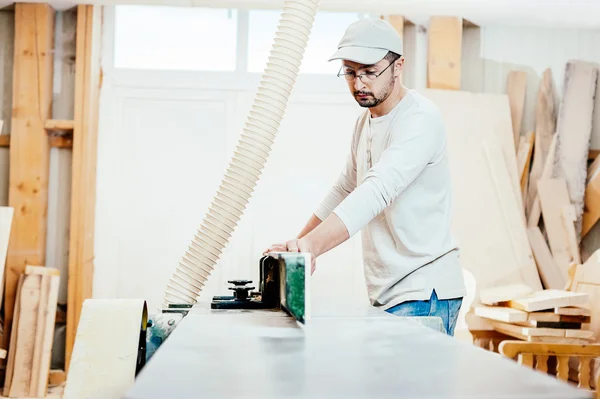 Carpinteiro trabalhando cortando algumas placas, ele está usando óculos de segurança e proteção auditiva — Fotografia de Stock