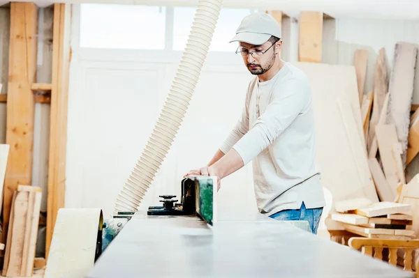 Charpentier travaillant sur des planches à découper, il porte des lunettes de sécurité et une protection auditive — Photo