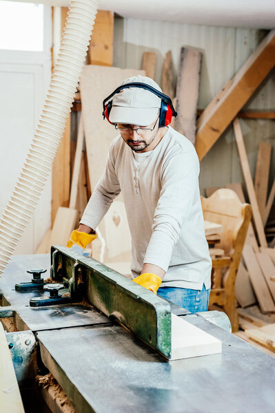 Carpenter working cutting some boards, he is wearing safety glasses and hearing protection