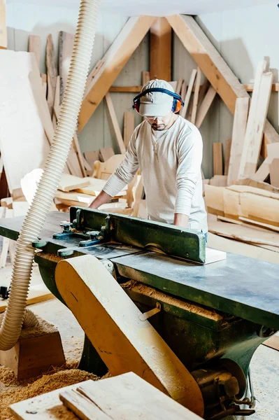 Carpinteiro trabalhando cortando algumas placas, ele está usando óculos de segurança e proteção auditiva — Fotografia de Stock