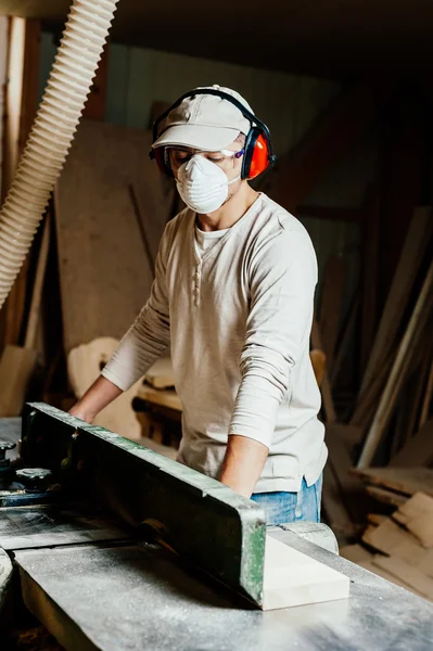 Carpenter working cutting some boards, he is wearing safety glasses and hearing protection