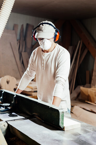 Плотник работает на деревообрабатывающей машине на заводе
