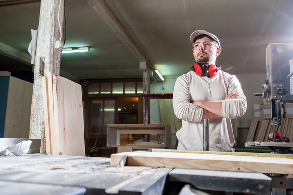 Carpintero trabajando con herramienta industrial en fábrica de madera con gafas de seguridad y protección auditiva . —  Fotos de Stock