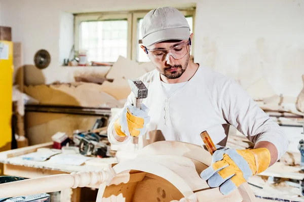 Carpenter working at a wood table with hammer and chisel. — Stock Photo, Image
