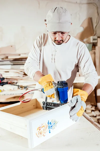 Carpenter working assembling a drawer with a screwdriver, he is wearing safety glasses protection — Stockfoto