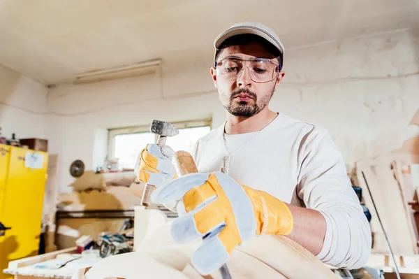 Carpintero trabajando en una mesa de madera con martillo y cincel . —  Fotos de Stock