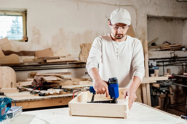 Carpintero trabajando ensamblando un cajón con un destornillador, lleva protección de gafas de seguridad —  Fotos de Stock