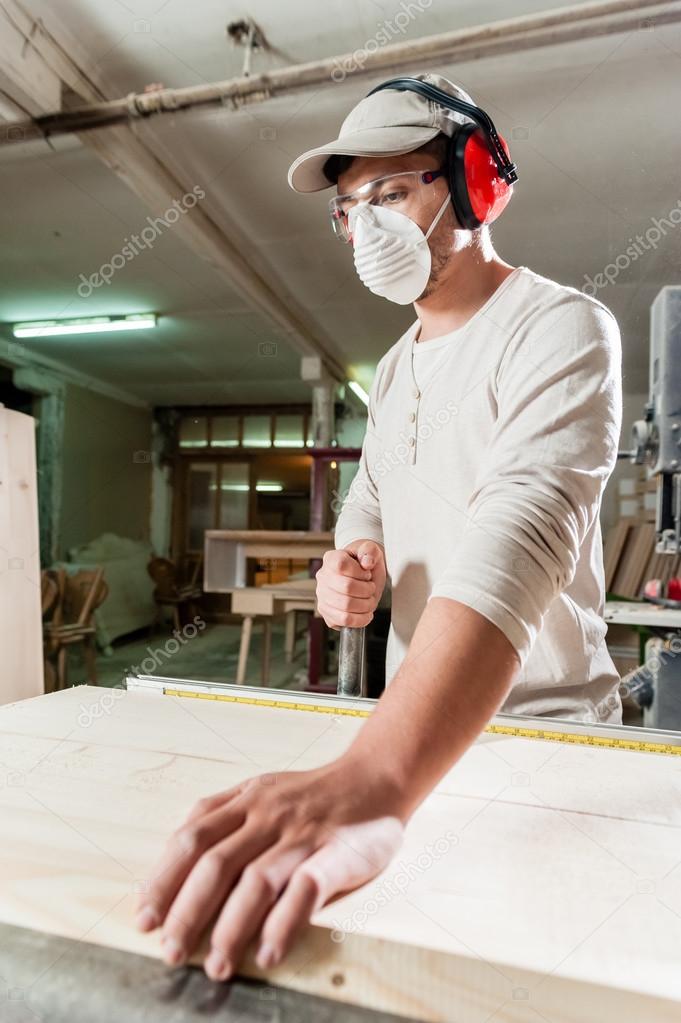 Carpenter working on wood machine in factory