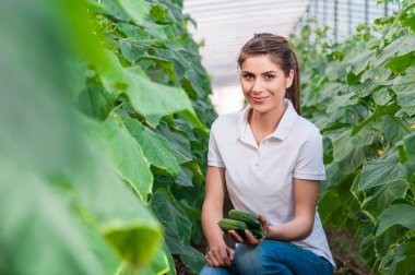Happy Young woman holding cucumbers