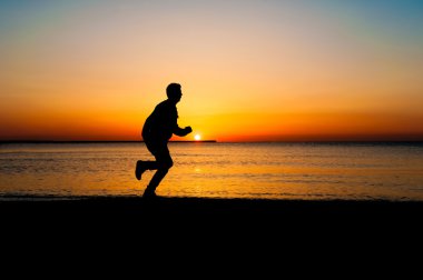 Adam kumsalda güneş doğarken çalışan siluet