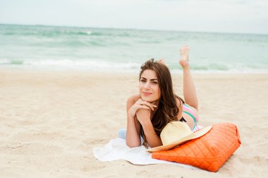 genç kadın bir plajda denize yakın oturan güneşin tadını