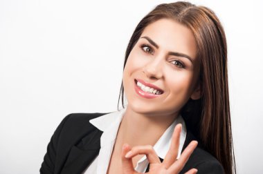 mutlu neşeli genç iş kadını ile iyi bir jest, gri arka plan üzerinde gülümseyen