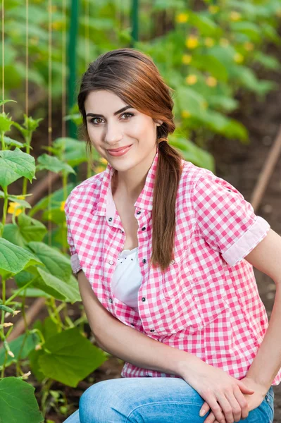 Piękna młoda kobieta ogrodnictwo i uśmiecha się do kamery. — Zdjęcie stockowe
