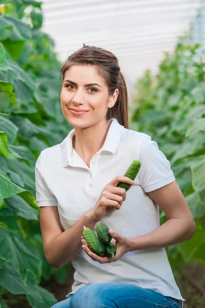Happy Young woman holding cucumbers — Stockfoto