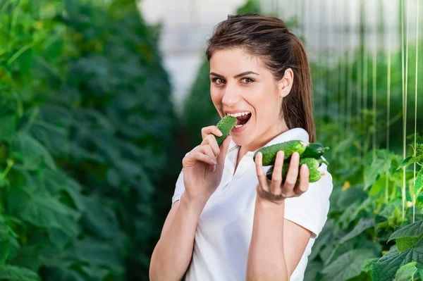 Щаслива молода жінка тримає і їсть огірки — стокове фото