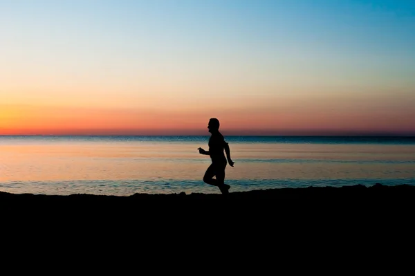 Sylwetka kolejny mężczyzna na plaży w sunrise — Zdjęcie stockowe
