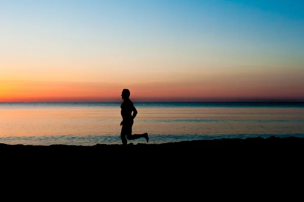 Silhouette of running man on the beach at sunrise — Stock Photo, Image