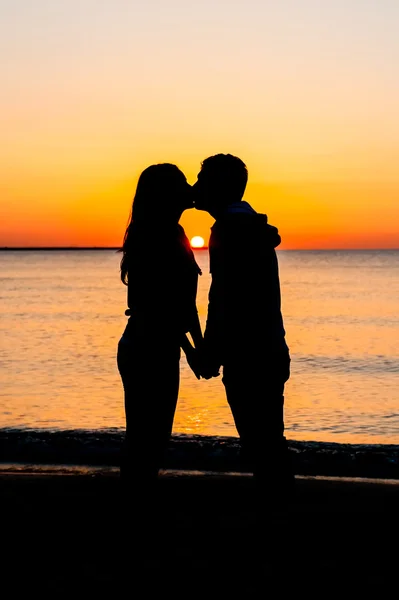 Silhouet van het paar andere zoenen op het strand bij zonsopgang. — Stockfoto