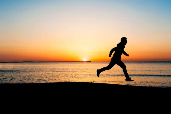 Silhouette of running man on the beach at sunrise — Stock Photo, Image