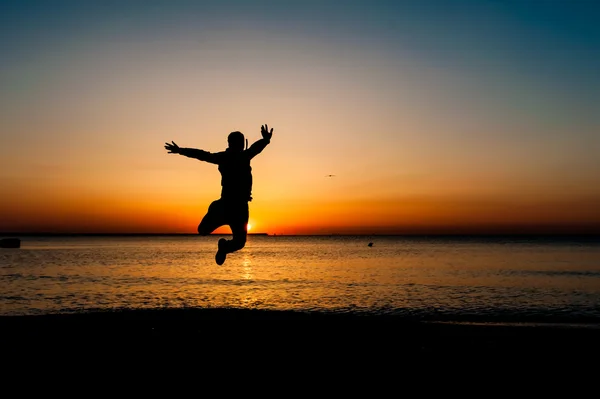 Sylwetka człowieka skoki w powietrzu na plaży na wschód. — Zdjęcie stockowe