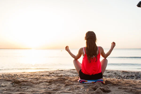 Silhouette young woman practicing yoga on the beach at sunrise. — Stock Photo, Image