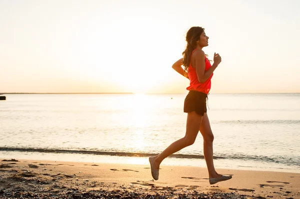 Mujer corriendo en la playa durante el entrenamiento . — Foto de Stock