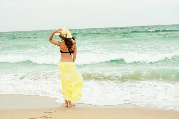 Denize yakın poz bir şapka ve sarı bir elbise giymiş bir güzel kız portresi — Stok fotoğraf