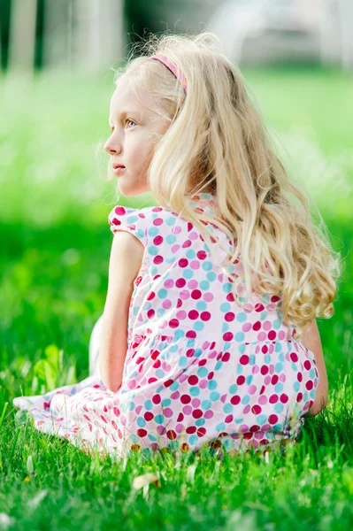 Portret van een blonde meisje opleggen van groen gras, buiten schieten — Stockfoto