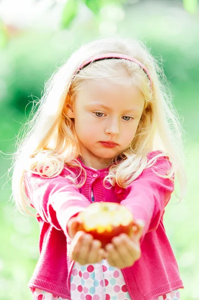 Pretty little blonde girl holding a bitten apple, an looking sad — ストック写真