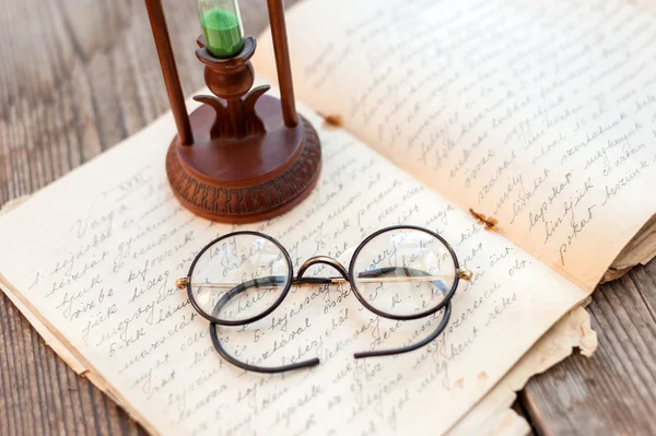 Vetro ora e vecchi libri su sfondo di legno — Foto Stock