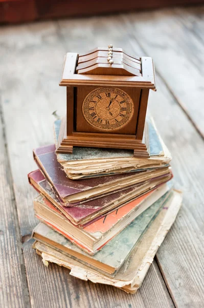 Libros antiguos y reloj de madera viejo sobre fondo de madera — Foto de Stock