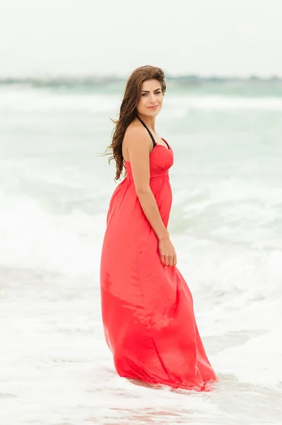 Young woman in a red dress on the ocean coast. Stock Image