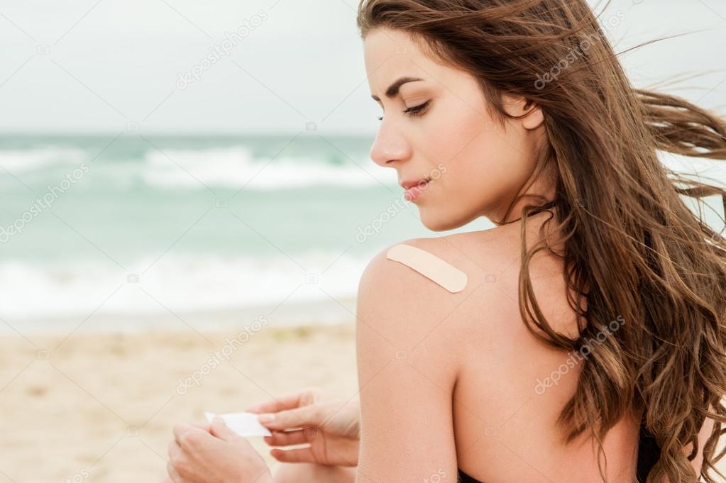 Woman at the beach with a band aid on her upper back