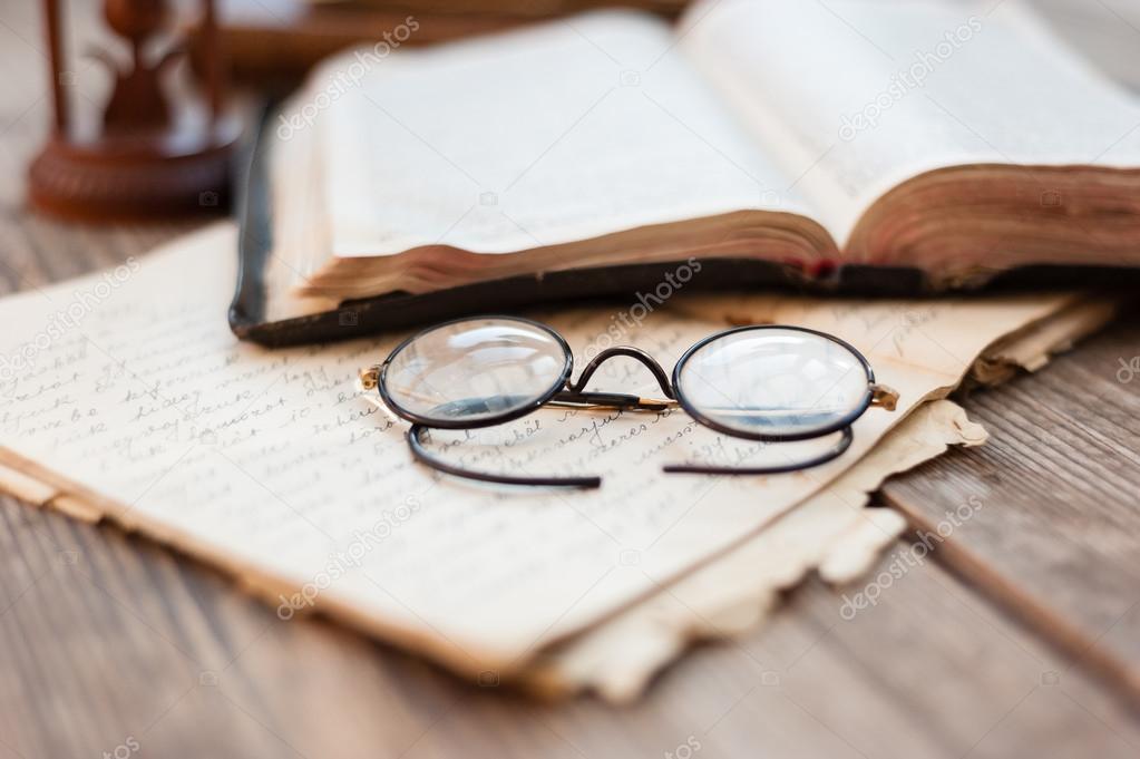Old books and old eyeglasses on wood background