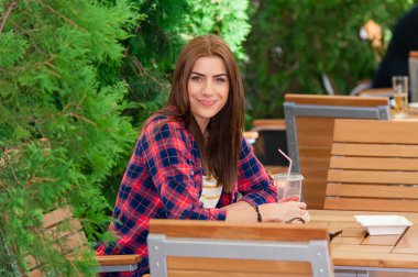 Woman on a coffee shop terrace in the street, drinking.
