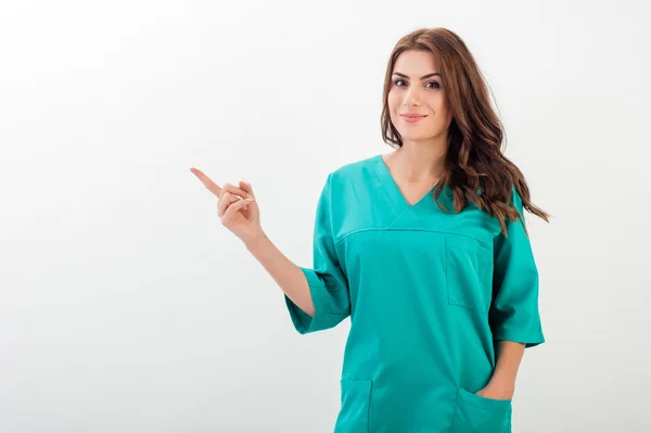 Medical doctor woman smile with stethoscope, nurse wear surgery suit, point finger to side, — ストック写真