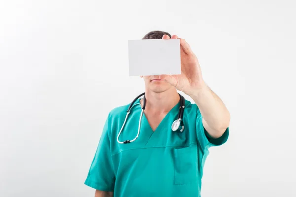 Nurse guy on blue medical uniform holding a white card on isolated background - copyspace — Stock Photo, Image