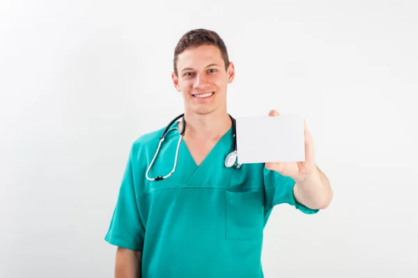 Enfermero con uniforme médico azul sosteniendo una tarjeta blanca sobre un fondo aislado - espacio de copia —  Fotos de Stock