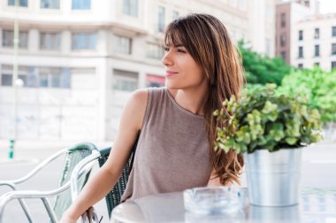 Young woman in the city taking a brake at a restaurant terrace.