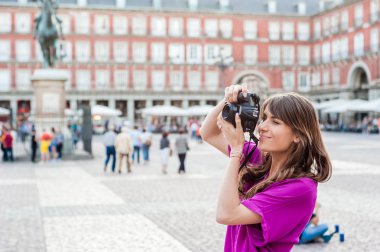 Bir fotoğraf makinesi, oturma ve kare, Plaza Mayor binalarda bakarak tutan genç kadın turist Madrid, İspanya