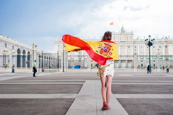 Young woman in front of Palacio de Oriente - the Royal Palace of Madrid, holding a flag. — Stockfoto