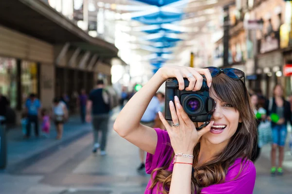 Young woman tourist holding a photo camera and taking picture in Plaza del Sol square, Madrid, Spain. — Stock Photo, Image