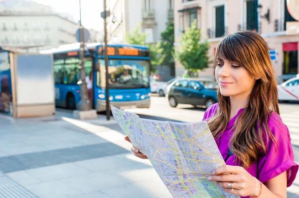 Junge Touristin mit einer Karte in der Hand in einer Bushaltestelle, auf der Suche nach Richtung Madrid, Spanien. — Stockfoto