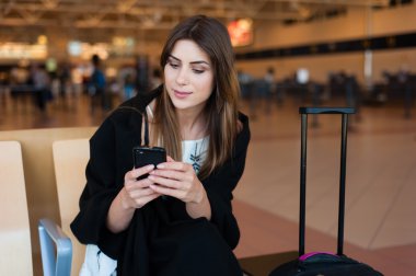 Genç kadın yolcu kapısında terminalde bekleyen akıllı telefon