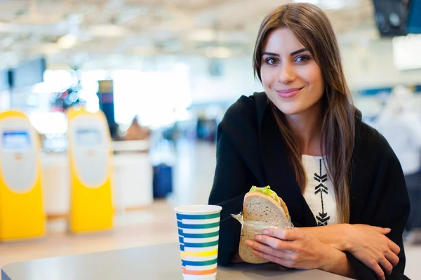 Young woman at international airport, drinking coffee while waiting for her flight. — Stock Photo, Image